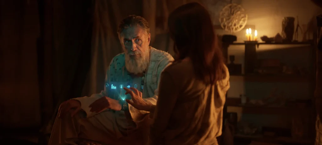 An older man with a beard interacting with a glowing holographic interface in a candle-lit room, scene from the film Sanctuary